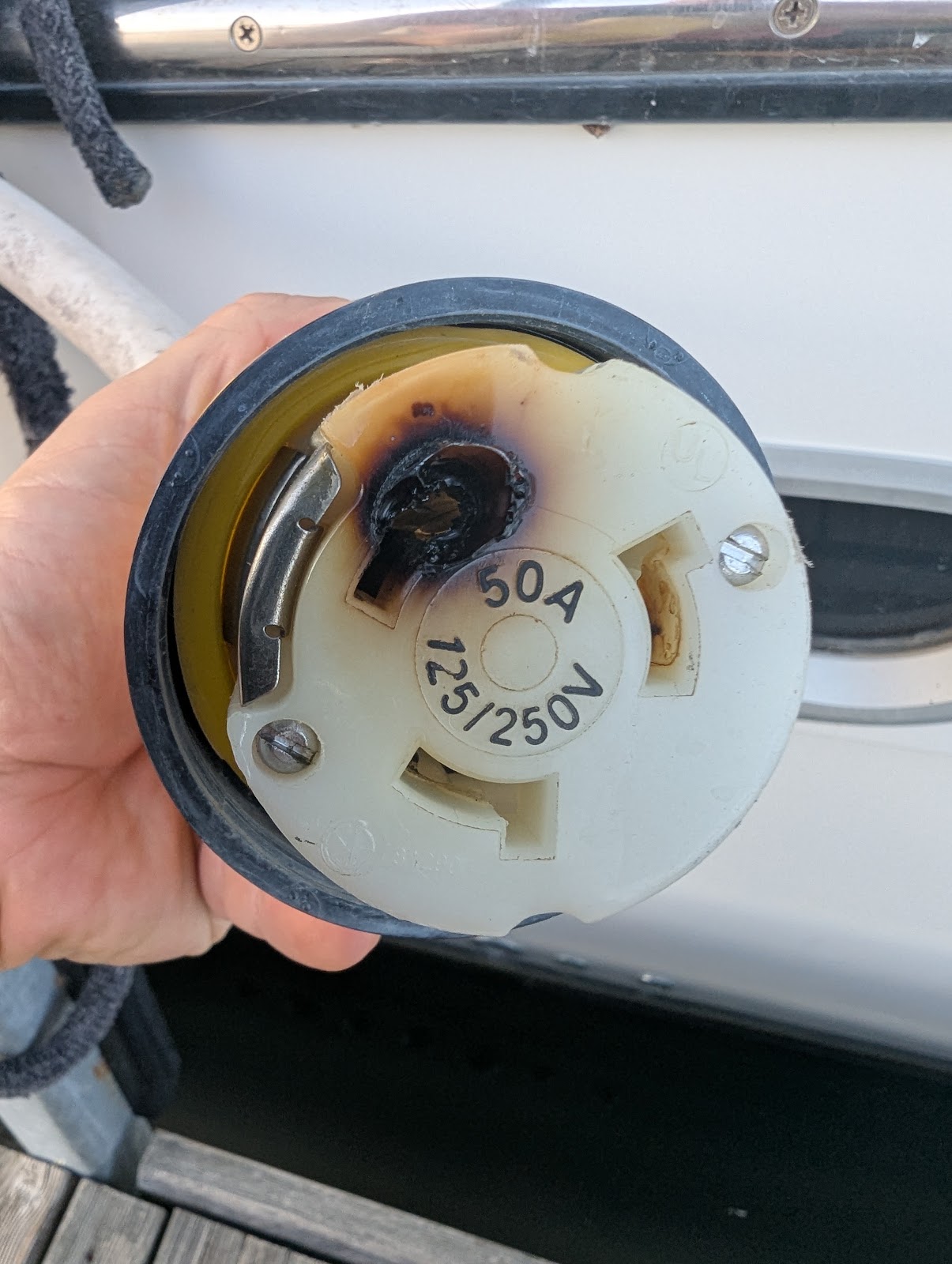 Burned contact and heat-damaged face on the original 50 A shore-power cord connector